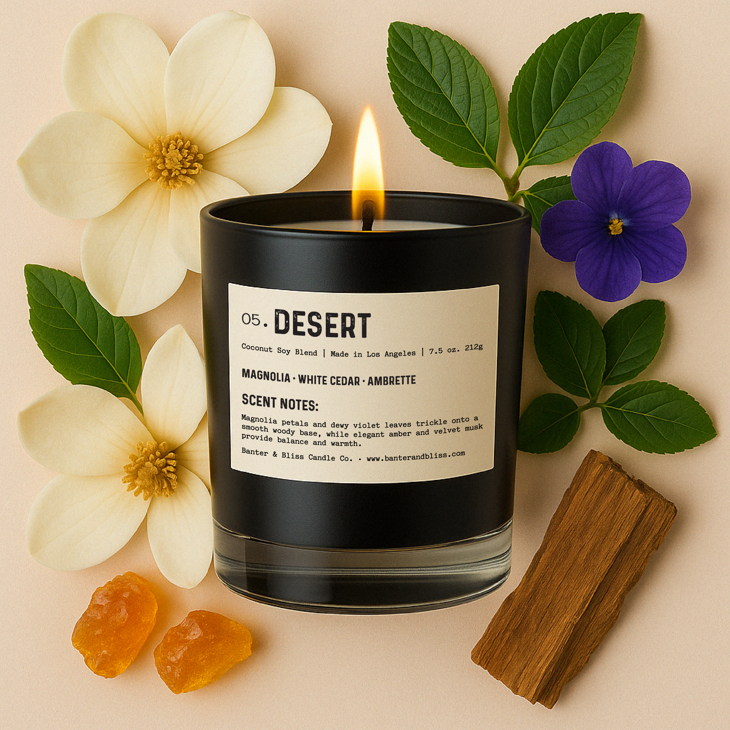 Flat lay of a lit black candle labeled “05. DESERT” with magnolia petals, violet flower, green leaves, amber resin, and cedar wood arranged around the base on a beige background, creating a luxe, fragrance-inspired composition.