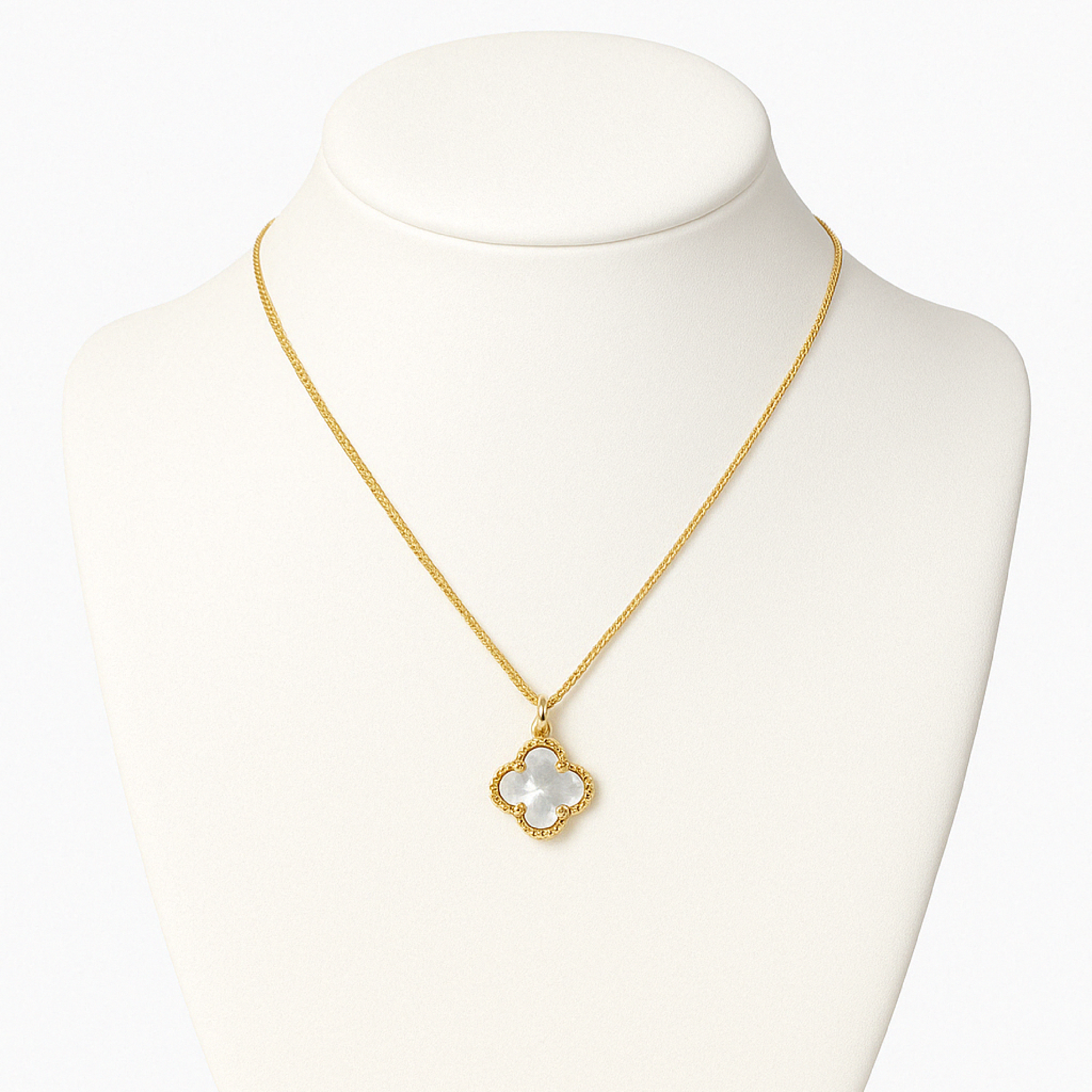A product photo of a gold necklace displayed on a white jewelry bust against a clean white background. The necklace features a clover-shaped mother-of-pearl pendant with a beaded gold border, centered neatly on the bust for a professional e-commerce presentation.