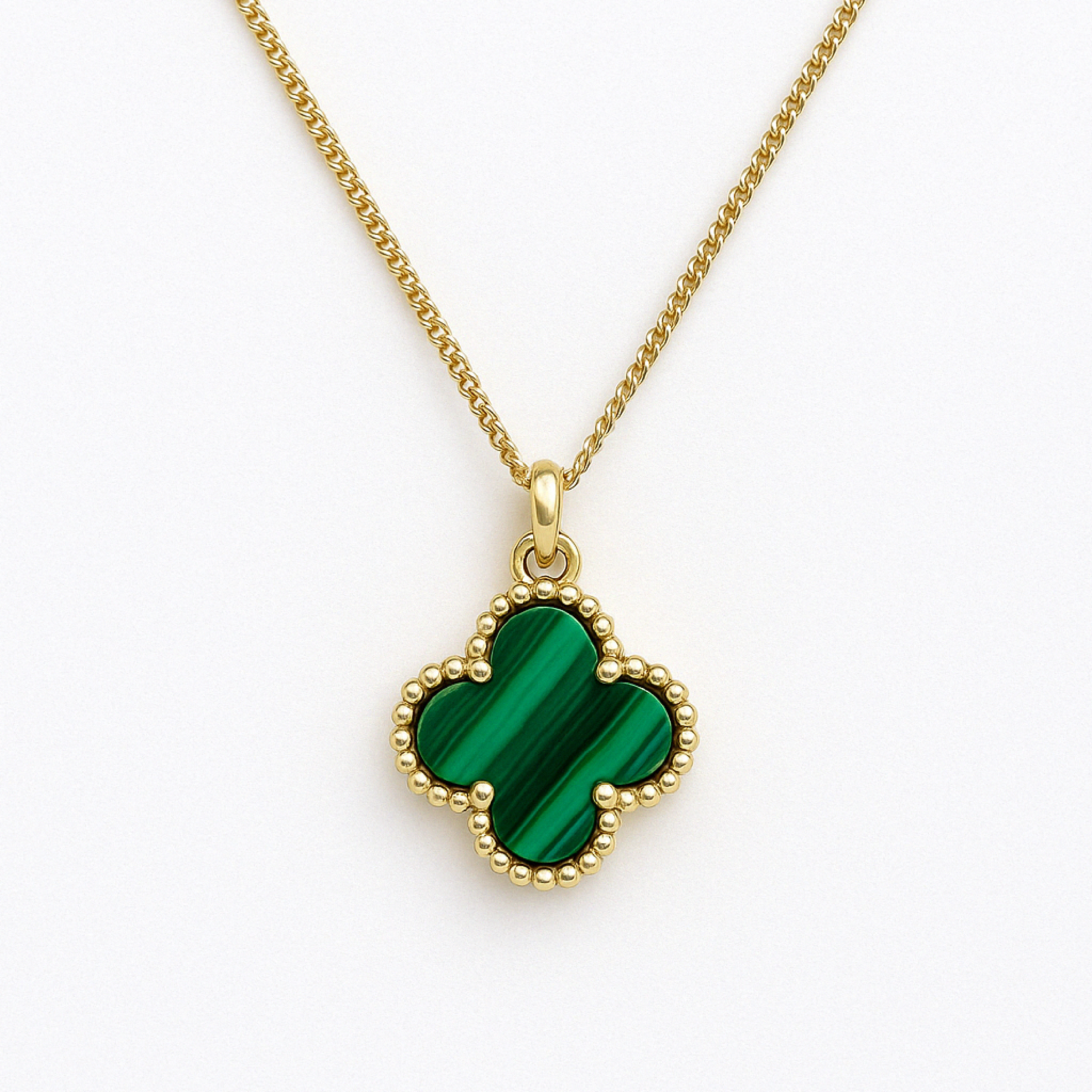 Close-up image of a green malachite clover-shaped pendant with a beaded gold border on a gold chain, displayed against a white background.