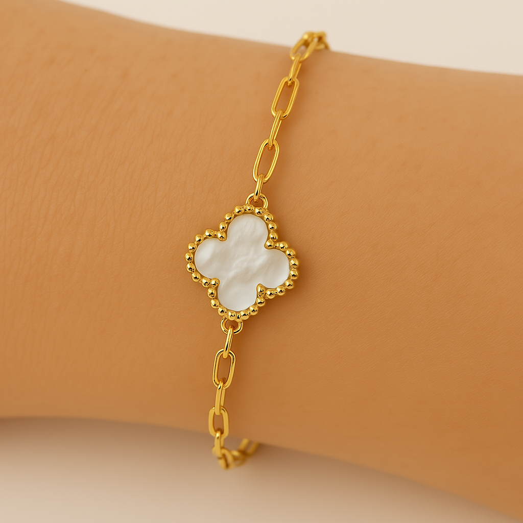 Close-up of a gold chain bracelet featuring a white mother of pearl clover charm with beaded edges, worn on wrist — elegant and feminine fine jewelry accessory.