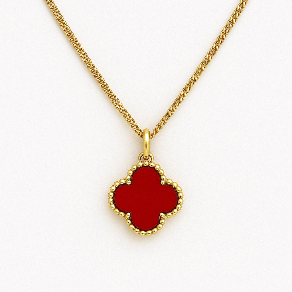 Close-up image of a gold necklace with a red clover-shaped pendant, featuring a beaded gold border. The necklace is centered and neatly arranged on a clean white background, with soft lighting highlighting the polished gold chain and glossy red enamel pendant.