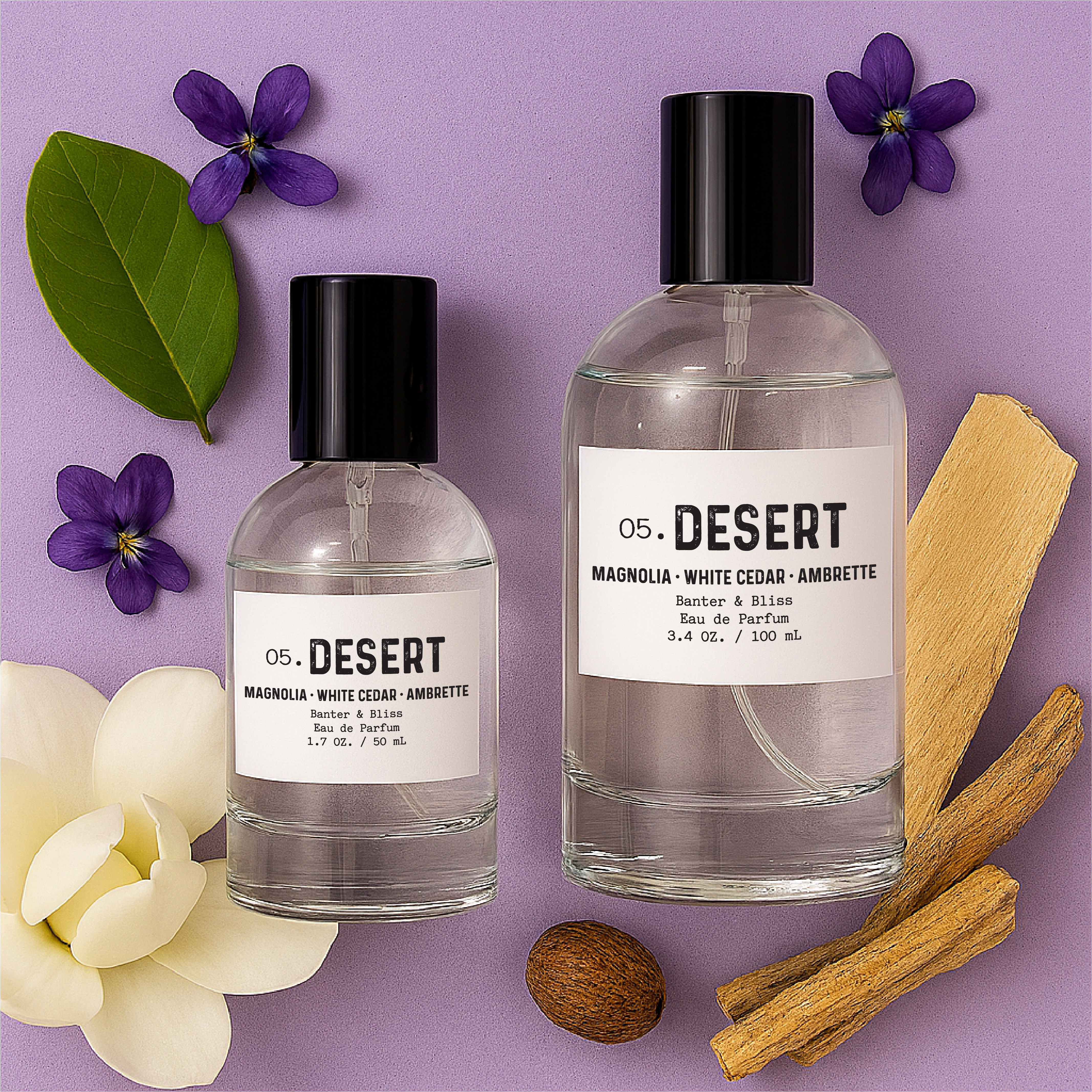 Desert Eau de Parfum by Banter & Bliss – flat lay of 1.7 oz and 3.4 oz clear glass perfume bottles with minimalist black caps, styled on a soft lavender background and surrounded by scent notes of magnolia petals, violet flowers, white cedarwood, orris root, ambrette seed, and sandalwood chips.
