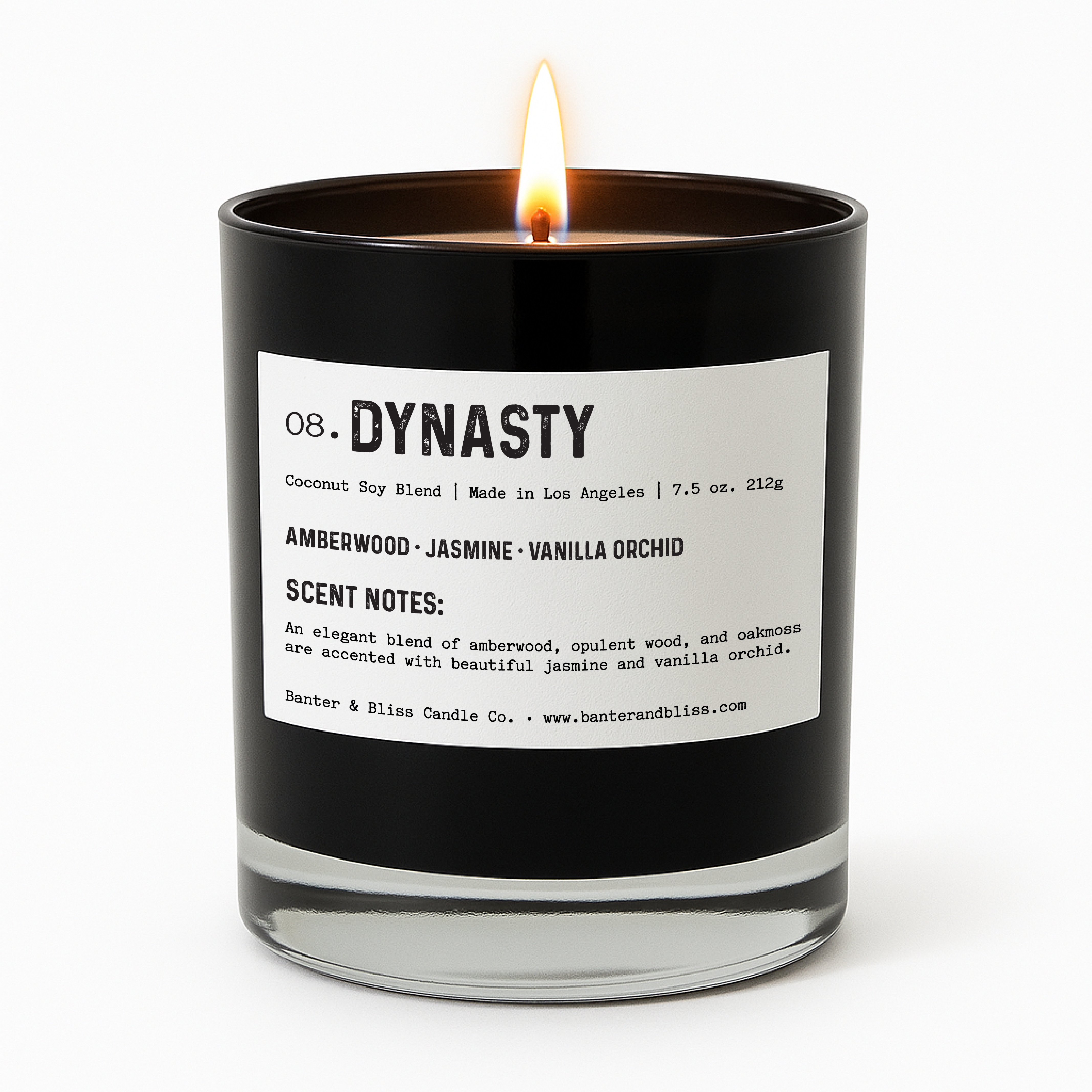 A lit black glass candle labeled "Dynasty" from Banter & Bliss Candle Co., with a white label featuring scent notes of amberwood, jasmine, and vanilla orchid. The candle stands upright against a clean white background.