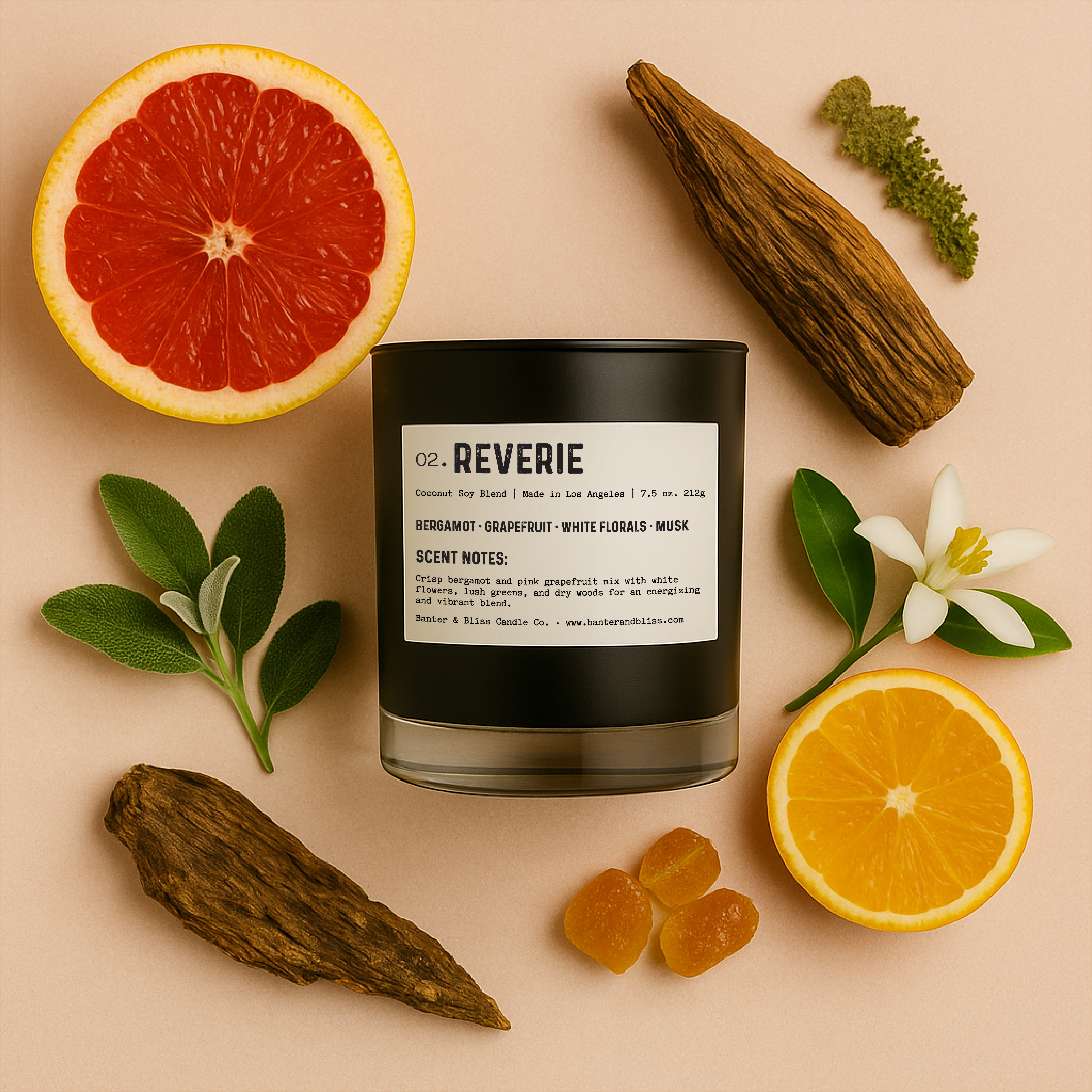 Flatlay of Banter & Bliss "Reverie" candle in a matte black glass jar with label, styled with fresh grapefruit, orange blossom, sage, vetiver, oakmoss, and amber resin on a pastel peach background — featuring scent notes of grapefruit, bergamot, white florals, musk, and dry woods.