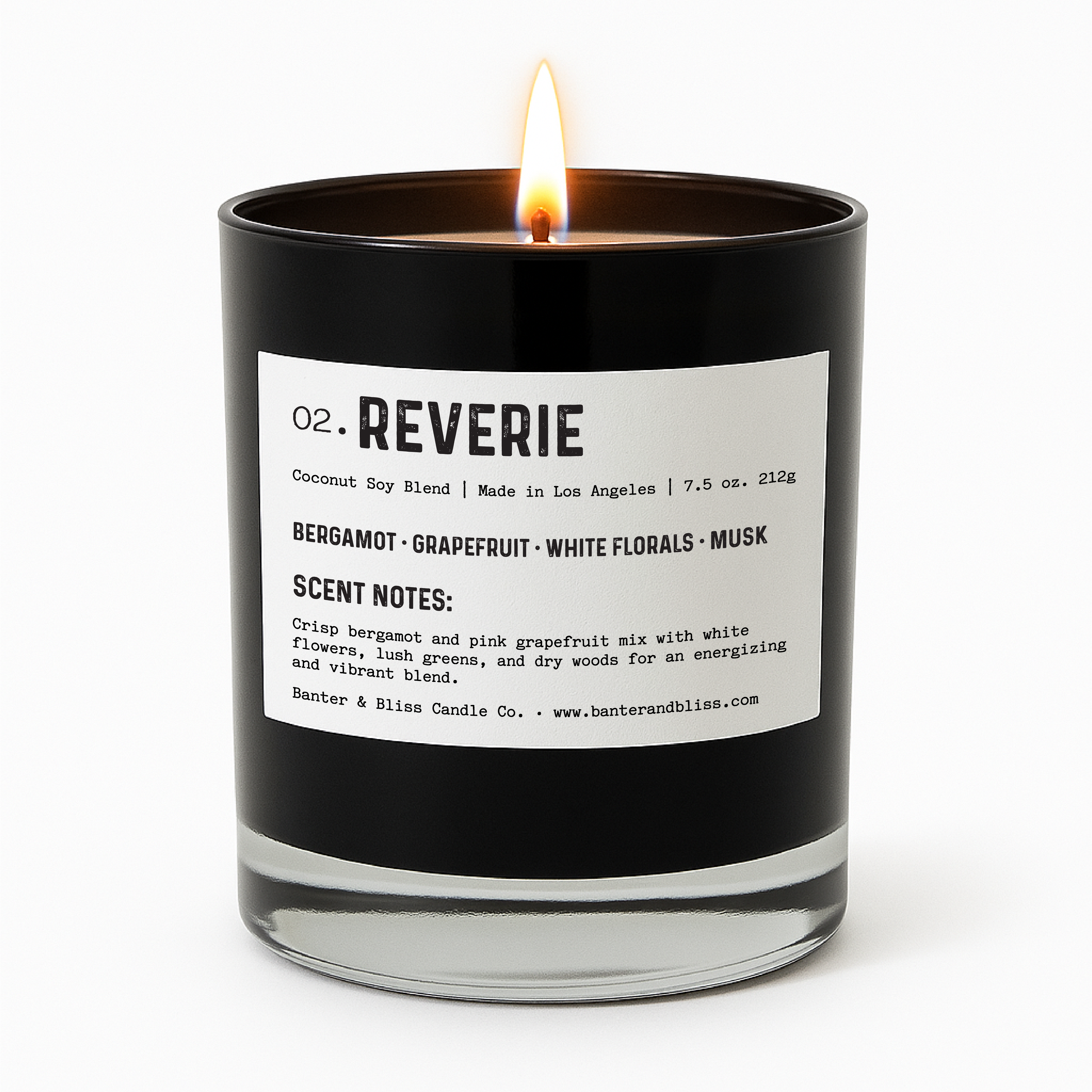 Banter & Bliss "Reverie" candle in a black glass jar with white label, lit and styled for product display — featuring scent notes of bergamot, grapefruit, white florals, musk, and dry woods. Coconut soy blend, made in Los Angeles.
