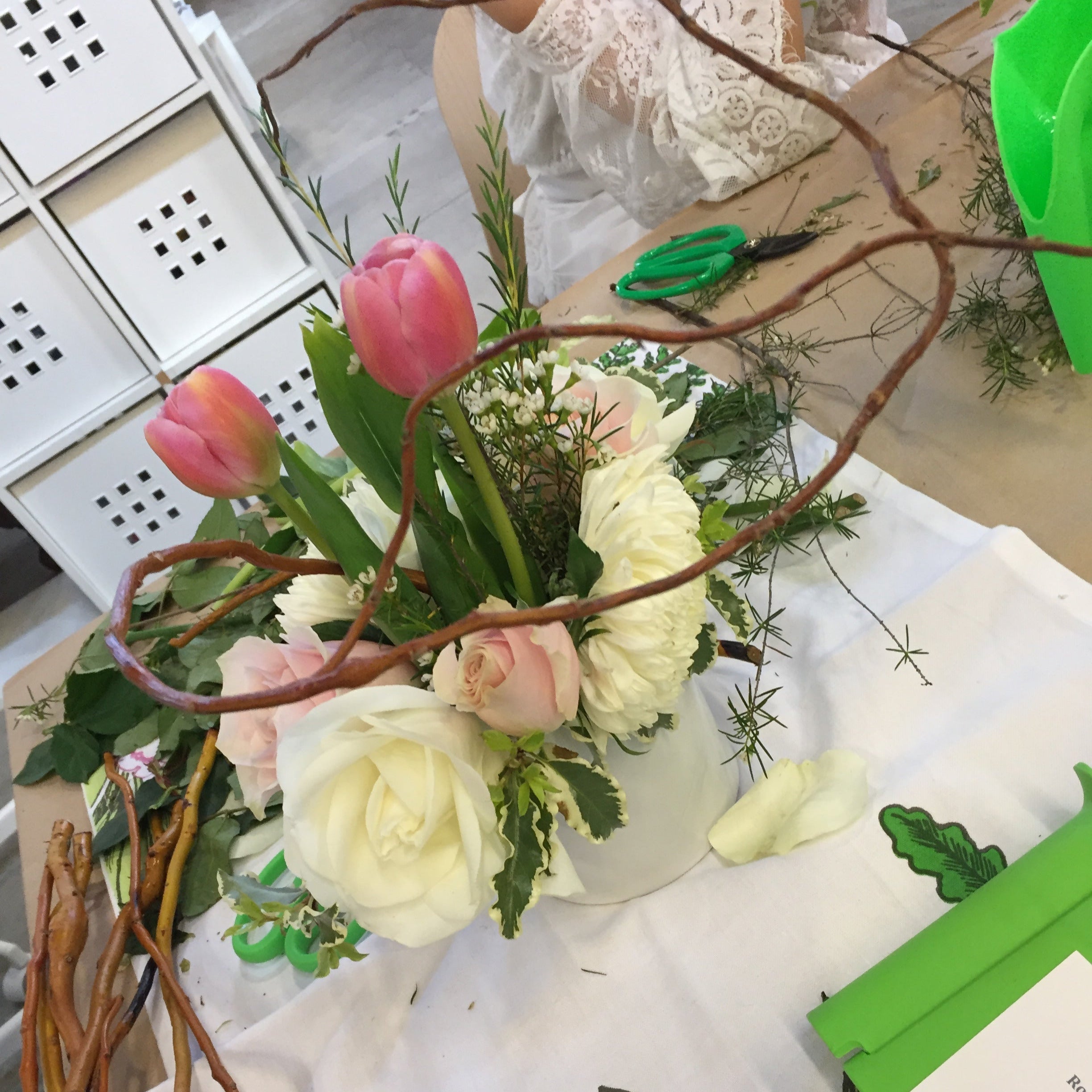 A finished flower arrangement  from a Banter & Bliss workshop, supplies and tools on a table